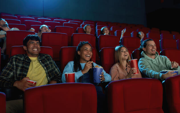 3 mensen in de cinema met popcorn, ze lachen